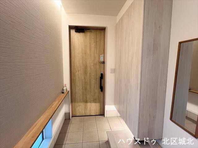 木目調ドアとアクセントクロスが映える玄関。ベンチ付きで荷物の出し入れや身支度もスムーズです。