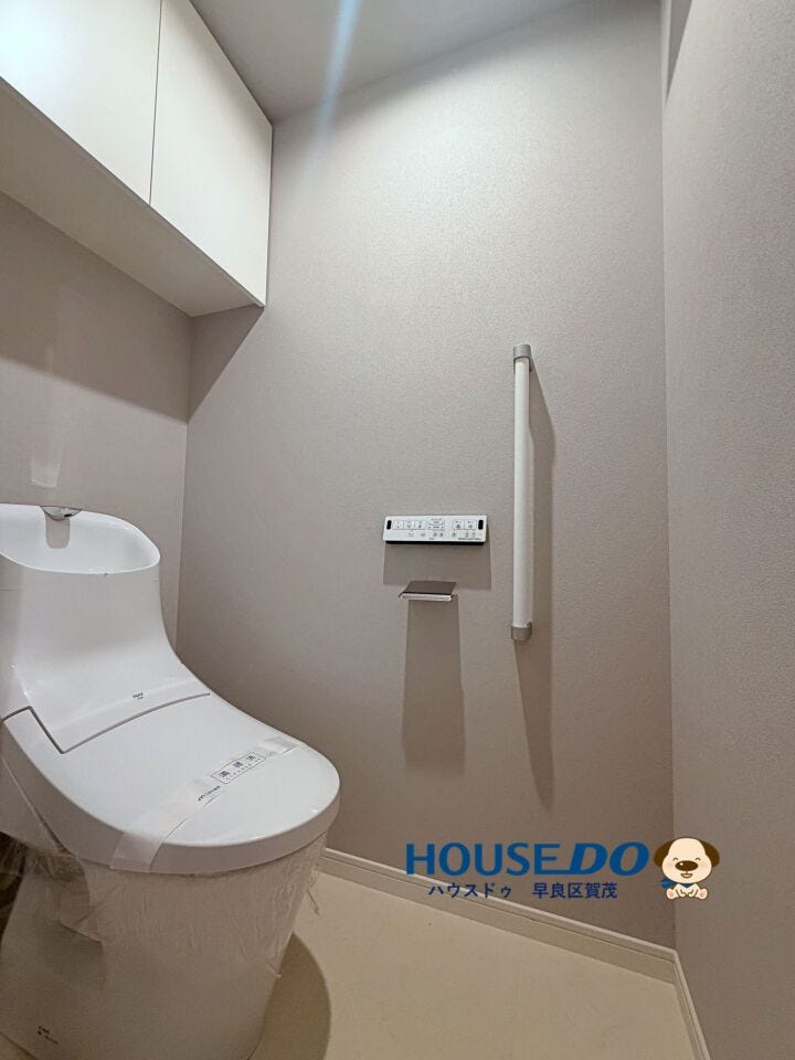 温水洗浄便座付きのトイレ。
上部には吊戸棚があるので、トイレットペーパーや掃除用品をしまっておけます