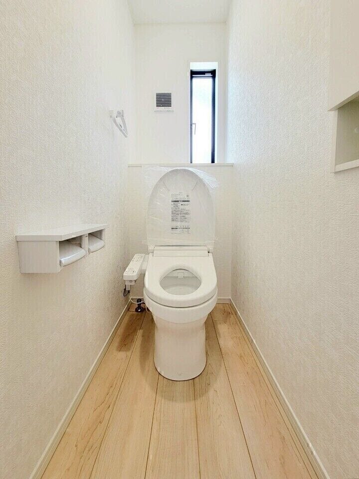 白を基調とした清潔感のあるトイレです。後方にはちょっとした小物を飾れるスペースがあります。