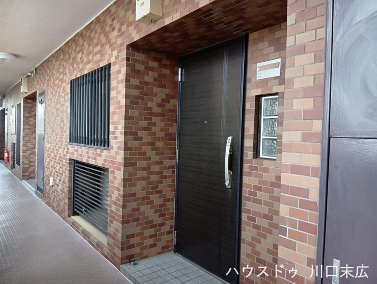 タイル張りの外壁と調和する、落ち着いた色合いの玄関ドア。住まいの顔として、訪れるゲストを品格ある佇まいで迎え入れます。