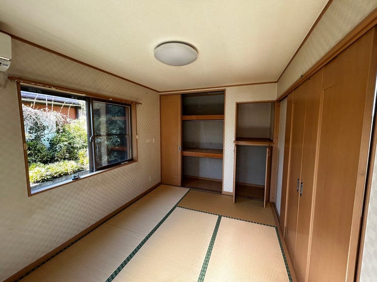 畳の香りが落ち着く和室です。壁面には大容量の押入れと、中段で仕切られた収納スペースを完備しています。掃き出し窓からは庭の緑が望め、採光も確保されています。戸を開放すれば隣室との一体利用も可能です。