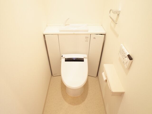 手洗器と収納を備えたトイレは、生活感を抑えたスマートな空間。床がすっきり片付き、掃除もしやすく快適です。