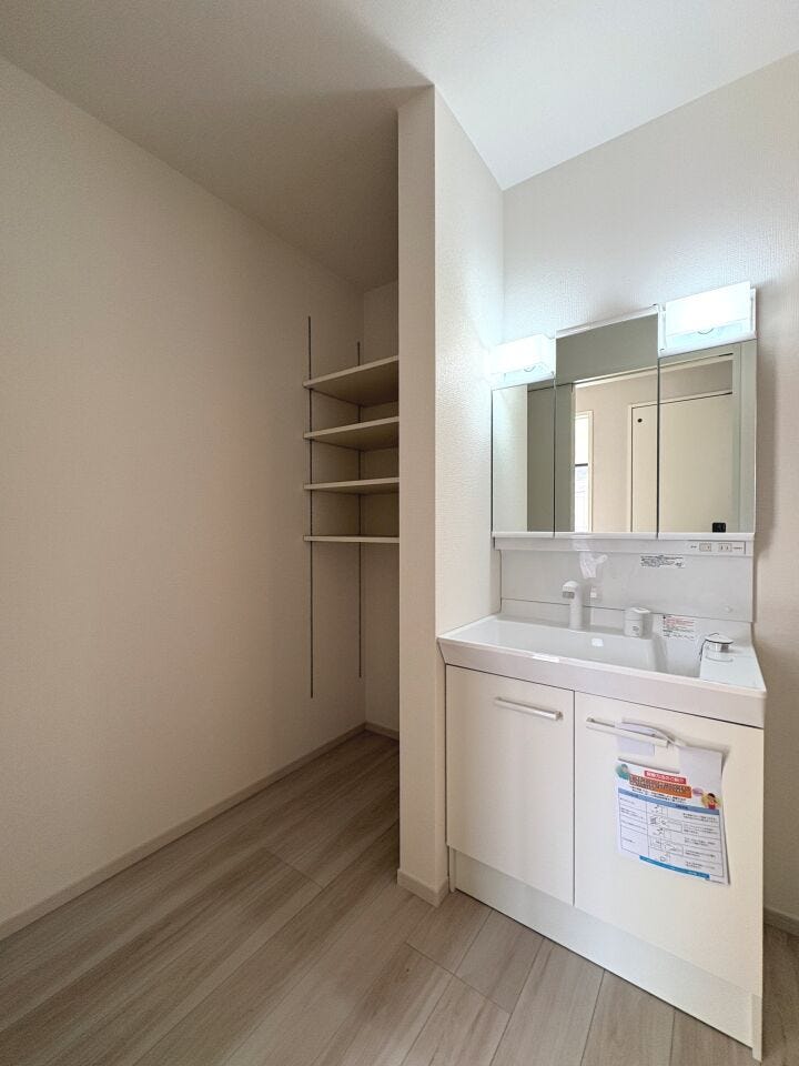 シャワー機能付き三面鏡の洗面化粧台。可動棚付きの洗面室でリネン類の保管も◎