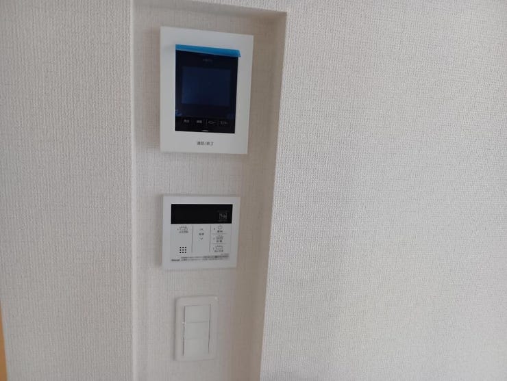 訪問者の顔を室内から確認できるモニター付インターホンと、給湯器の操作パネルをまとめて配置しています。ご家族の安全な暮らしと、毎日の快適なバスタイムを支える機能的な設備です。