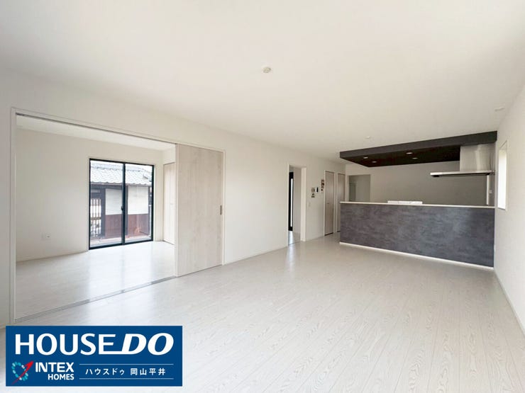 キッチンからリビング全体が見渡せる開放的な設計!お料理中もリビングにいるご家族と繋がっていられます。白を基調とした内装に、キッチンのダークカラーがアクセント。