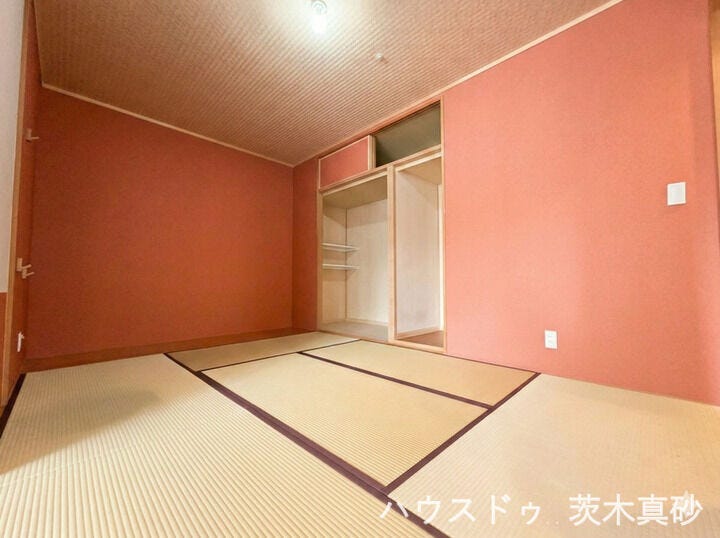 【モダンな彩り×充実収納】
温かみのある赤壁が印象的な和室。
便利な棚付き収納を備え、くつろぎと実用性を両立した空間です。