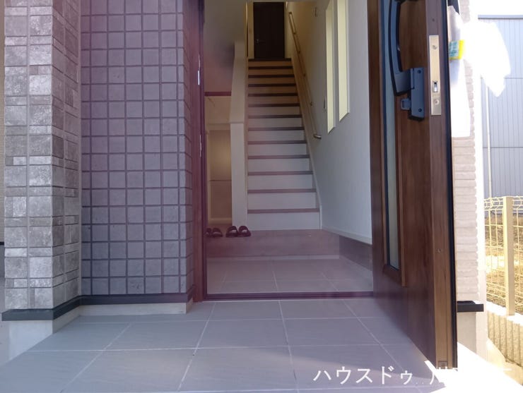 重厚感のある木目調の玄関ドアを採用したアプローチ。ご家族の帰りやゲストを温かく迎え入れる、落ち着きと気品を兼ね備えたエントランス空間です。