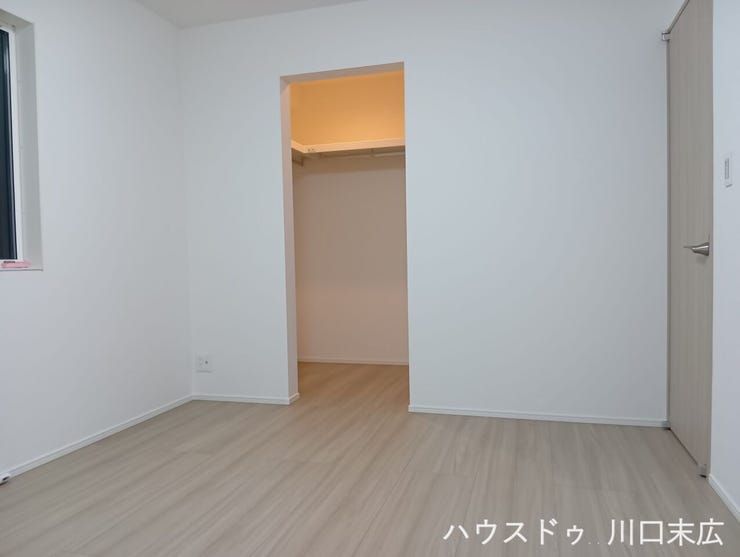 ウォークインクローゼットを備えた居室。木目調の床材が空間に温もりを与え、落ち着いた雰囲気を醸し出します。