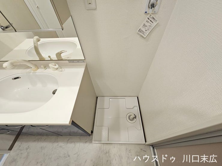 水漏れを防ぐ防水パンを備えた洗濯機置場。洗面化粧台と並んだ機能的な水回りレイアウトにより、入浴時の着替えや日々の洗濯動線をスムーズに整えます。