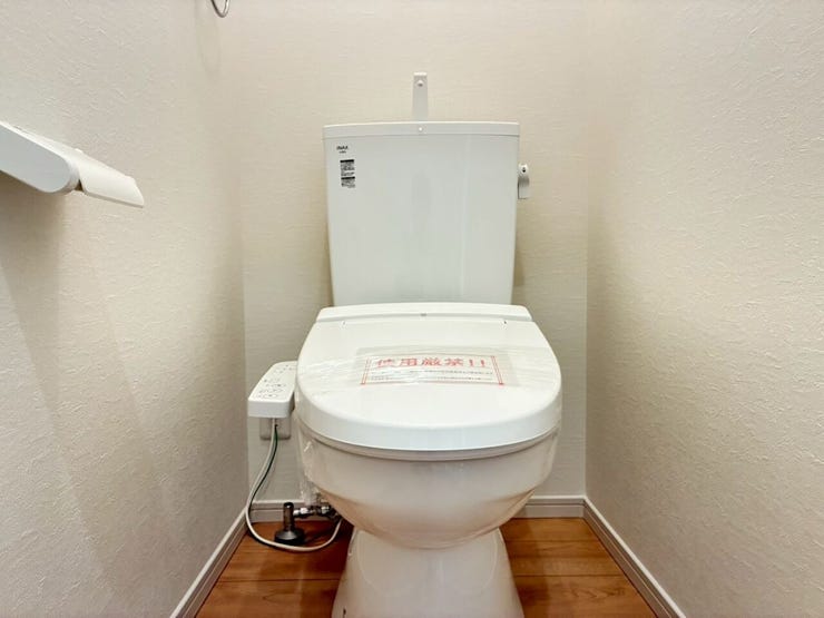 白を基調とした清潔感あふれるトイレスペースです。快適な温水洗浄便座や使いやすいペーパーホルダーなどの設備を完備。温かみのある木目調 of 床材が優しく調和し、ホッと落ち着ける心地よい空間を演出します。