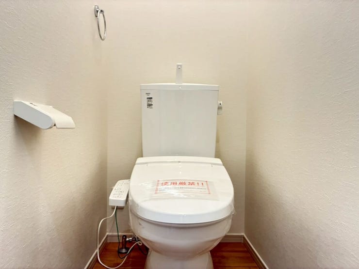 白を基調とした、清潔感のあるトイレスペースです。快適に使える温水洗浄便座やタオル掛け、ペーパーホルダーを完備。温かみのある木目調の床材がアクセントになり、落ち着きのある心地よい空間を演出します。
