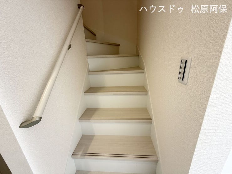 白木目調の段板と手すりが温かみのある階段スペース。窓からの自然光が差し込み、明るく清潔感あふれる空間です。手すりが設置されており、誰でも安心して長くお使いいただけるバリアフリー設計です。
