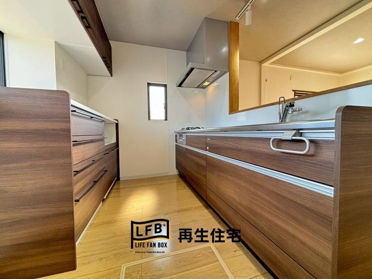 リビングを見渡せる対面式のシステムキッチン。スタイリッシュな木目調のデザインと、手元を照らすスポットライトが料理の時間を楽しく彩ります。