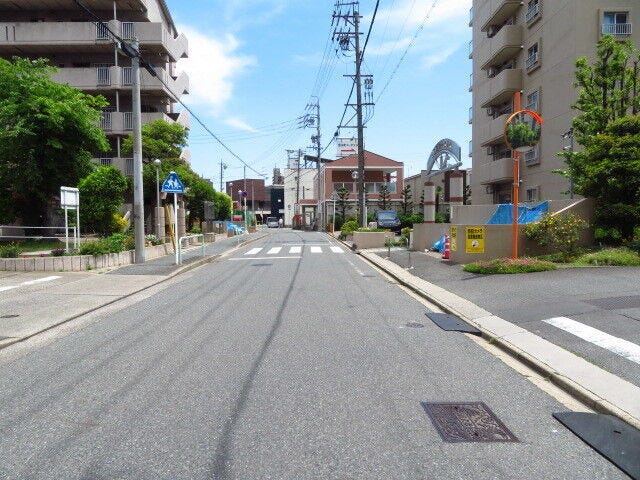 マンション東側前面道路です。写真右側が該当マンションの北側駐車場入り口にあたります。歩道があるので、お子様の通学も安心ですね。