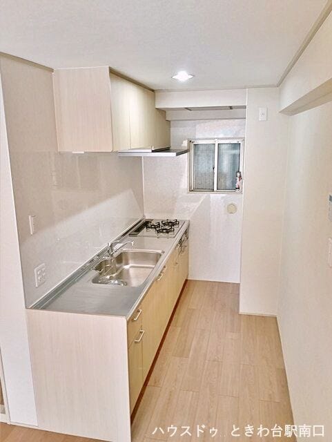 調理スペースを広く確保した、使い勝手の良い壁付け型キッチンです。上下に豊富な収納棚を備えており、調理器具や食器もスマートに収まります。小窓があるため換気もしやすく、快適にお料理を楽しめる環境です。