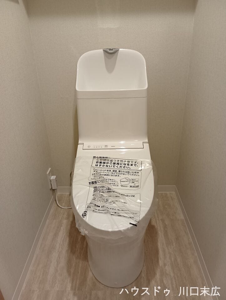 温水洗浄便座を備えた機能的なトイレ空間。手洗い付きのタンクを採用しており、日々の使いやすさと衛生的な環境を保つための配慮がなされた設計です。