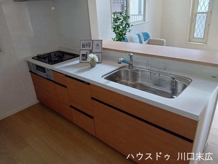 木目調のパネルが空間に調和する対面式キッチン。家事をしながらリビングにいるご家族との会話を楽しめる設計です。