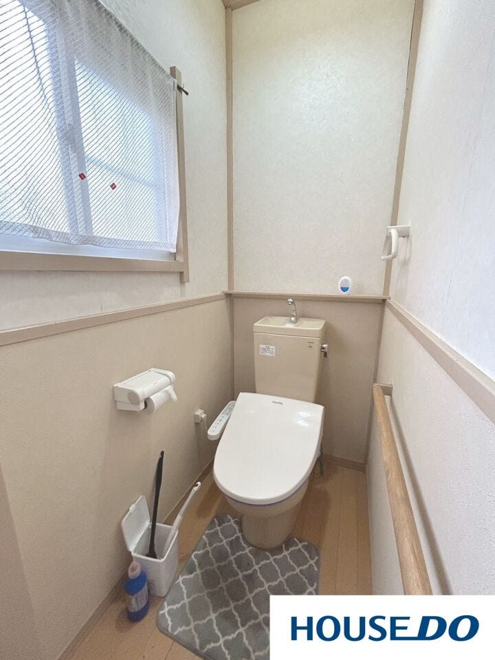 清潔感のある白を基調としたトイレです。温水洗浄便座付きで毎日快適。大きな窓があり、明るい日差しとスムーズな換気が確保されています。手すりも設置されており、どなたでも安心して利用できる設計です。