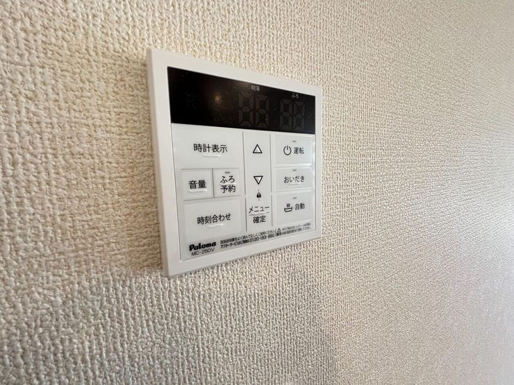 壁面に給湯器のリモコンが設置されています。浴室へ足を運ぶことなく、お風呂の自動お湯張りや追い焚き、温度調節の操作に対応しています。通話機能も備わっており、生活の利便性に配慮された設備設計です。