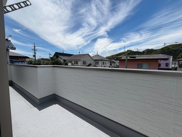 横幅の広いバルコニーです。壁面の上部には物干し金具が備わり、洗濯物を干す空間として活用する設計です。周辺に視界を遮る高い建物はなく、空を見渡す眺望が広がります。