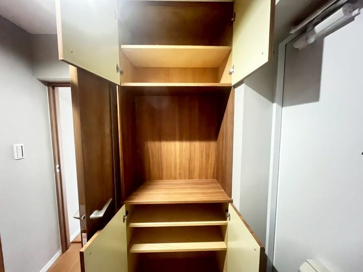 玄関に設けられた木目調の収納棚です。上下段には複数の棚板が配置され、靴類を整理して保管するスペースが確保されています。中央部のオープンスペースは、小物を置くカウンターとして活用可能な造りです。
