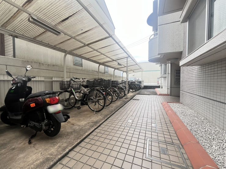 敷地内に設けられた屋根付きの駐輪スペースです。前面にはタイル張りの通路が確保されており、スムーズな入出庫に対応する共用部分です。