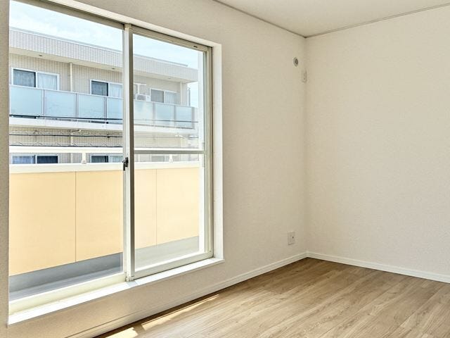大きな窓から心地よい光が差し込む明るい洋室