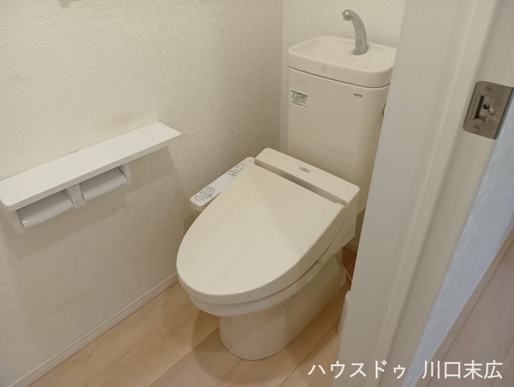 温水洗浄便座を備えた機能的なトイレ空間。手洗い付きのタンクレス風デザインで、スマートかつ清潔感のあるレストルームを実現しています。