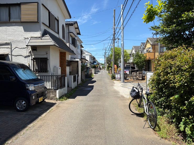青空が広がり、向こうまで見通せる開放的な前面道路。道幅もゆったりとしており、お車同士のすれ違いや駐車も落ち着いて行えそうです。日差しを遮るものがない明るい道は、毎日の通園や通学も足取りが軽くなります。