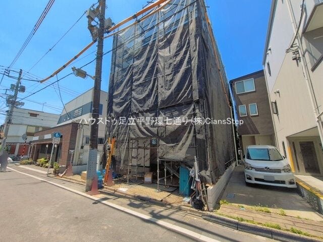 道路側から見た建築中の現地。敷地形状や隣接建物との位置関係を確認しやすい写真です。