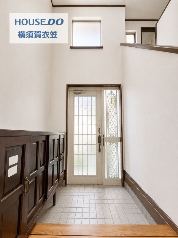 縦に広がる吹抜け玄関が開放感を演出。上部の窓からやわらかな光が入り、来客を気持ちよく迎えられる明るい空間です。