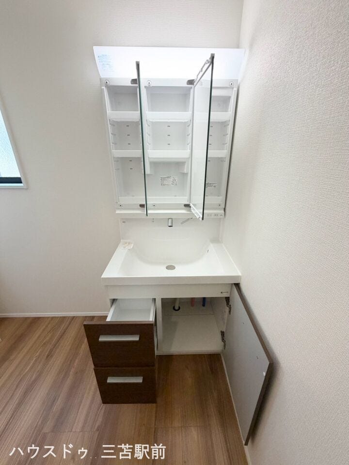 使いやすい三面鏡タイプの洗面化粧台。収納と明るい照明付き。
