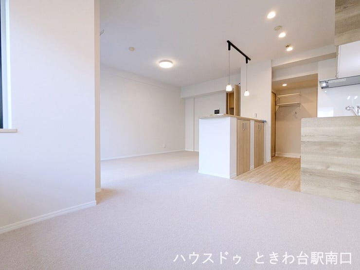 リフォームで美しく整えられたLDKは、木の温もりを感じるキッチンカウンターがアクセント。心地よい絨毯の感触とともに、家族がゆったりと寛げる空間となっています。