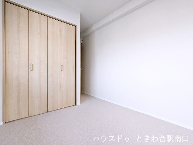 木目調の扉が落ち着いた雰囲気を醸し出す、壁面一面のクローゼットです。衣類などをまとめて収納できるため、居住スペースを有効に活用できます。明るい内装とも調和するデザインです。