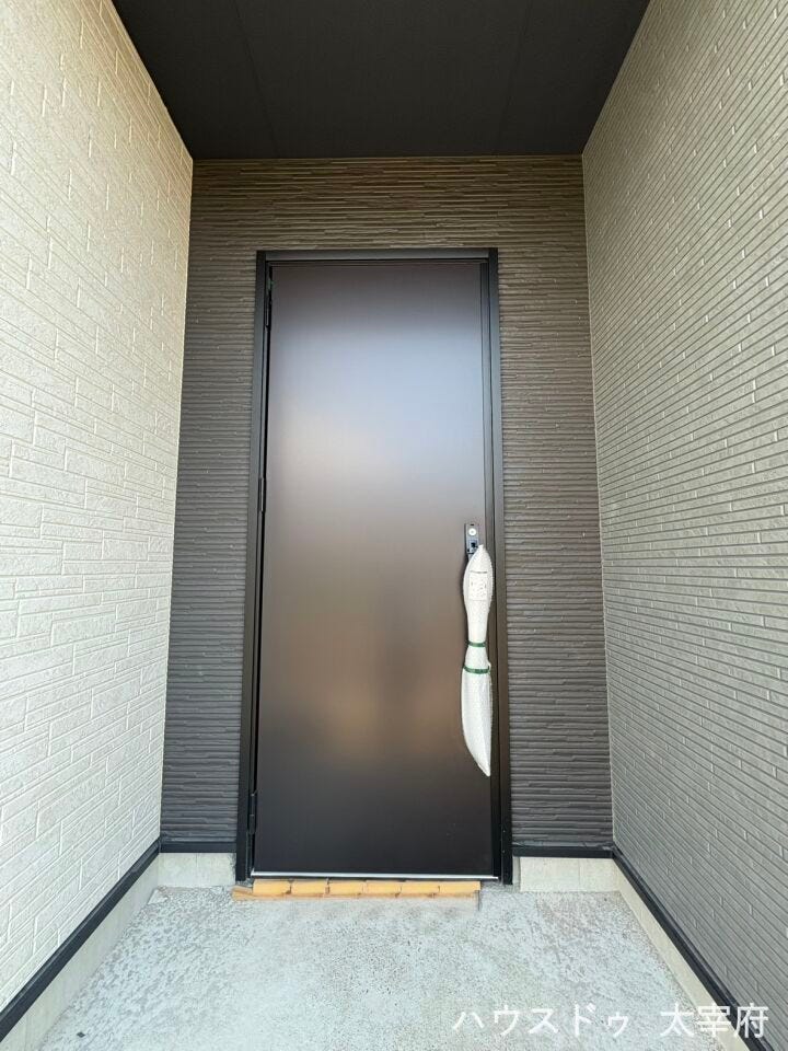 屋根付きのゆとりある玄関アプローチで、雨の日も安心して出入り可能です。重厚感のある玄関扉とタイル張りで上質な印象を与えます。