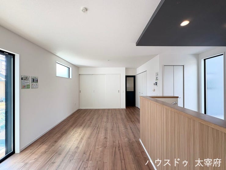 白を基調とした明るく開放的な空間に、スタイリッシュなアクセントクロスと折り下げ天井が映える洗練されたLDK。木目調の対面キッチンや複数の窓から光が差し込む、居心地の良いデザインが魅力です。