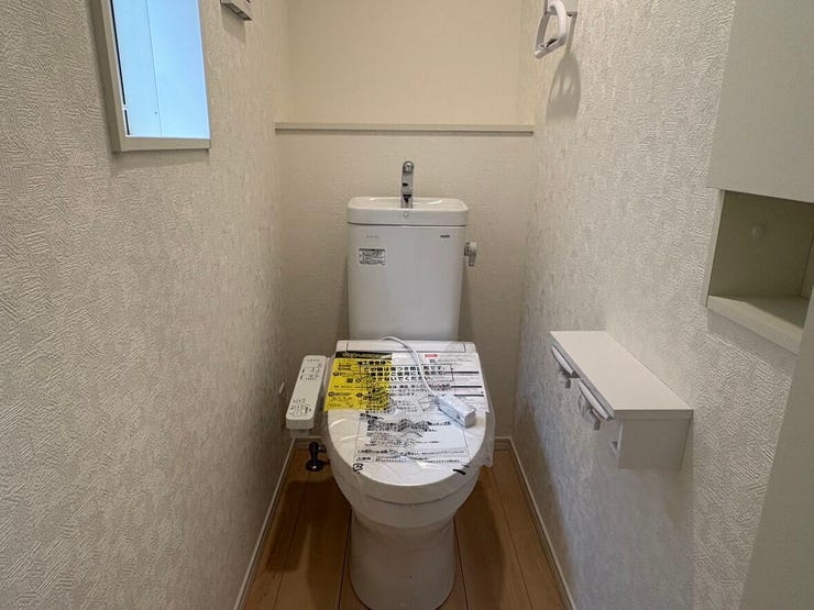 清潔感のあるホワイトで統一された、すっきりと心地よいトイレ空間です。ペーパーホルダーには小物を置ける便利な棚が付いています。小さな一輪挿しや芳香剤を飾って、自分好みの落ち着く場所にアレンジできそう。