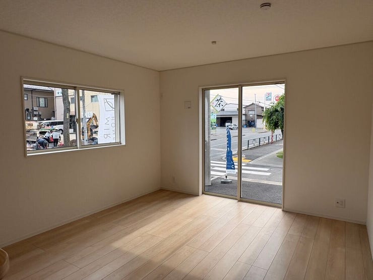 外の景色を身近に感じられる大きな掃き出し窓から、心地よい光が差し込むリビング。ナチュラルな木目調の床が、空間全体に温かみを添えています。家族みんなでゆったりとくつろげる、やわらかな印象の住まいです。