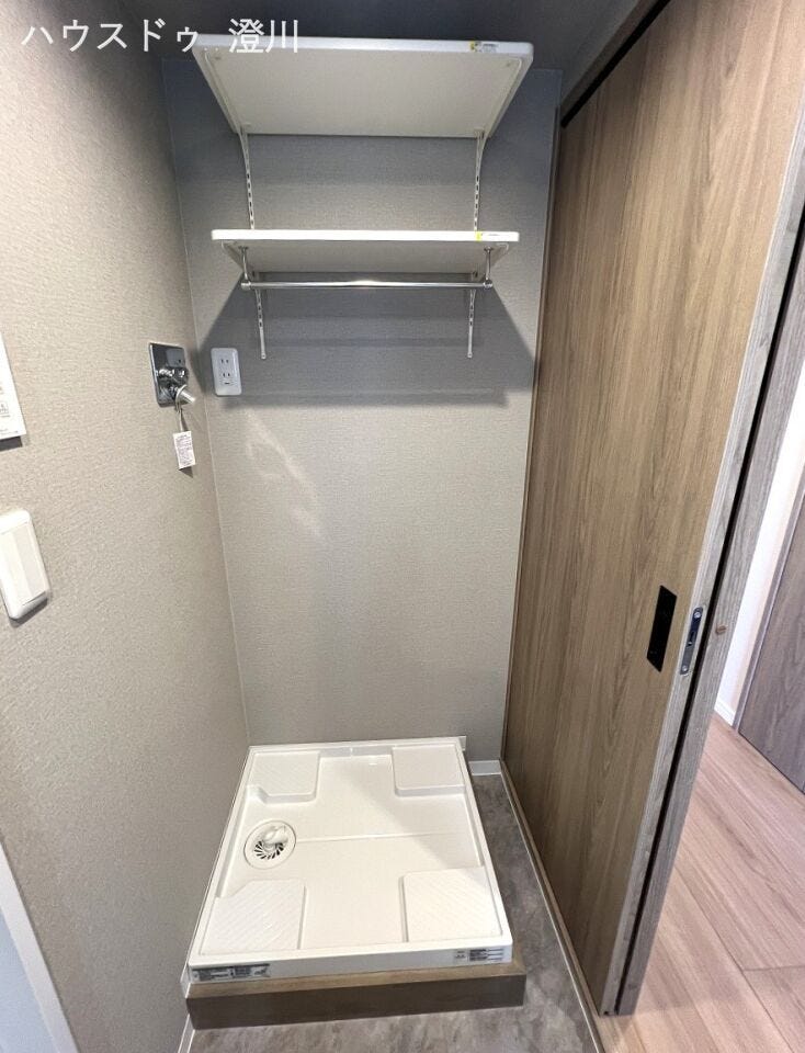 洗面室内に配置された使い勝手の良い洗濯機置き場。上部には洗剤や小物をすっきりと収納できる便利な棚を設けており、限られた空間を無駄なく効率的に活用できます。
