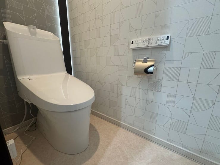 デザイン性にもこだわったトイレ空間。温水洗浄便座を完備し、シックな壁紙と木目調のカウンターが落ち着いた雰囲気を演出します