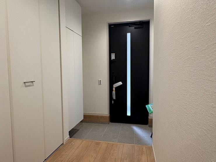 玄関扉のシックな黒色が清潔感のある白い空間を引き締めるモダンなエントランスです。背の高いシューズボックスを備え、玄関周りの靴をすっきりと収納できるため、来客時も広々とした印象を保てます。