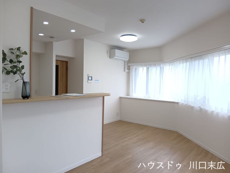 木目調の床材が温かみを演出する居住空間。家族との会話が弾む対面式キッチンを備え、安らぎの時間を過ごせるデザインに仕上がっています。