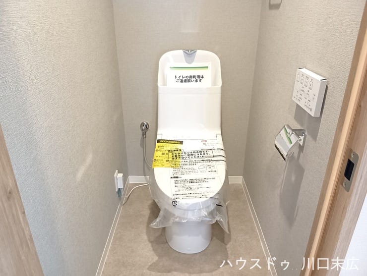 清潔感のある空間に設えられた、温水洗浄便座付きのトイレ。使い勝手の良い壁掛けリモコンを採用し、手元でスムーズに操作ができるすっきりとした設計です。