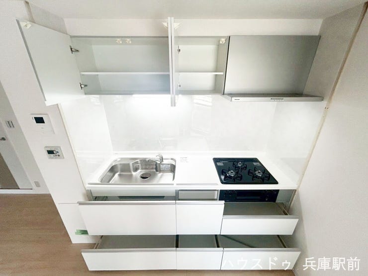 白を基調としたキッチン。収納スペースが確保されており、調理器具や食器類もすっきり整理しやすい仕様です。