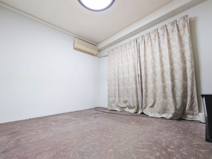 落ち着いた色味のカーペットが敷かれた洋室です。壁は白を基調とし、圧迫感の少ないシンプルな内装。大きな窓は採光にも配慮されています。