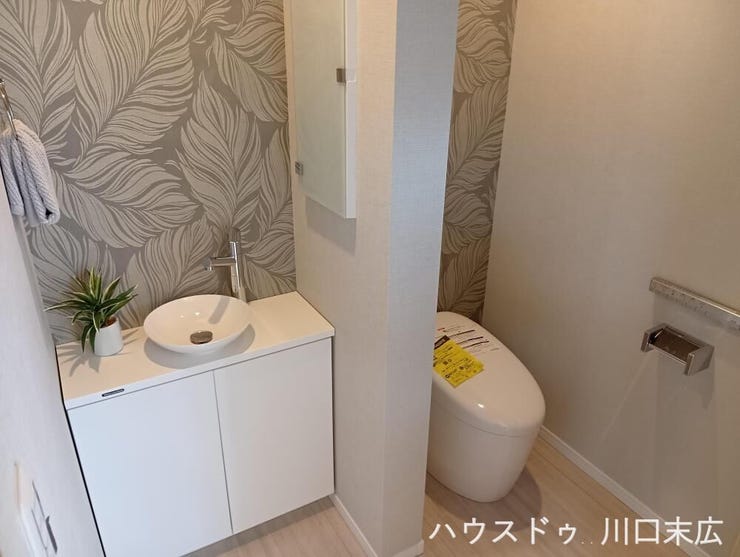 清潔感のある温水洗浄便座付きトイレ。手洗いボウルを備えたタンク一体型で、日々のお手入れもしやすく、心地よく整えられたサニタリー空間を維持します。