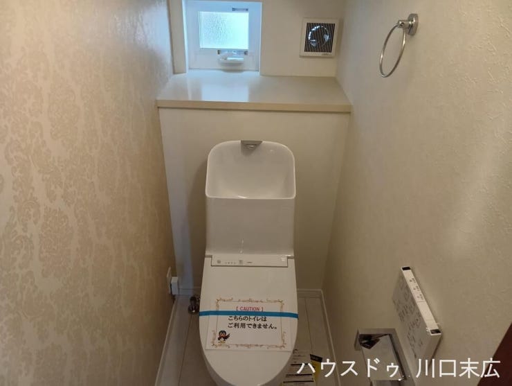 独立した手洗い器を備えた機能的なトイレ。アクセントクロスが空間に落ち着きを与え、日々のお手入れもしやすい設計です。