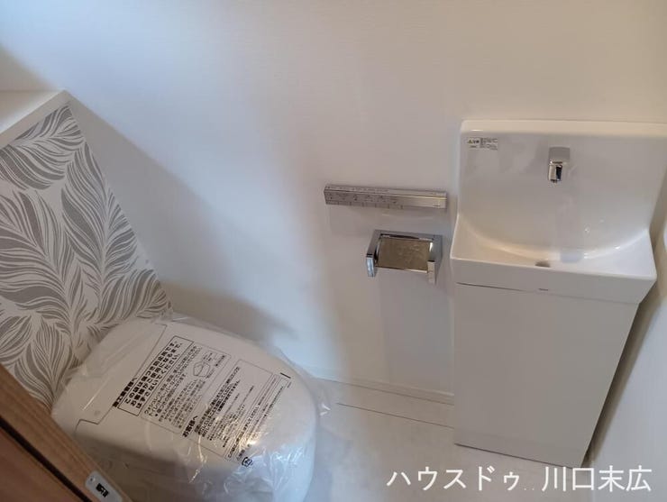 清潔感のある温水洗浄便座付きトイレ。手洗いキャビネットを備え、ゲストも快適に使用できるサニタリー空間です。
