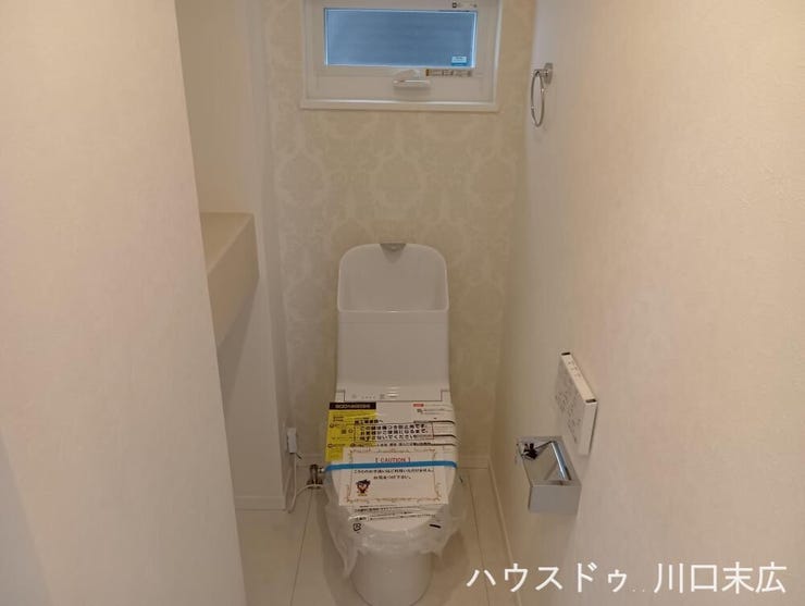 清潔感のあるデザインでまとめられた温水洗浄便座付きトイレ。ペーパーホルダーやタオル掛けなどの実用的な機能が整い、日々のお手入れもしやすい設計です。