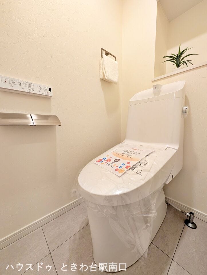 清潔感のある温水洗浄便座付きのトイレです。上部には吊戸棚を備えており、トイレットペーパーなどのストックもスマートに収納できます。